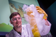 A member of the Public Programmes team in goggles and gloves with an experiment in a large test tube