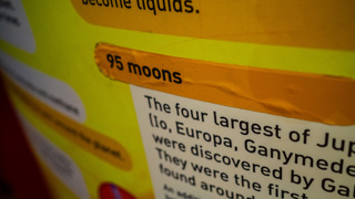 An orange sticker with 95 moons printed on it is stuck over the old exhibit details