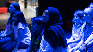 Families watching a talk and science demonstration in LIVE Space gallery
