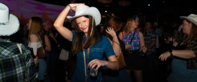 Lady tips her hat whilst dancing at Cosmic Country