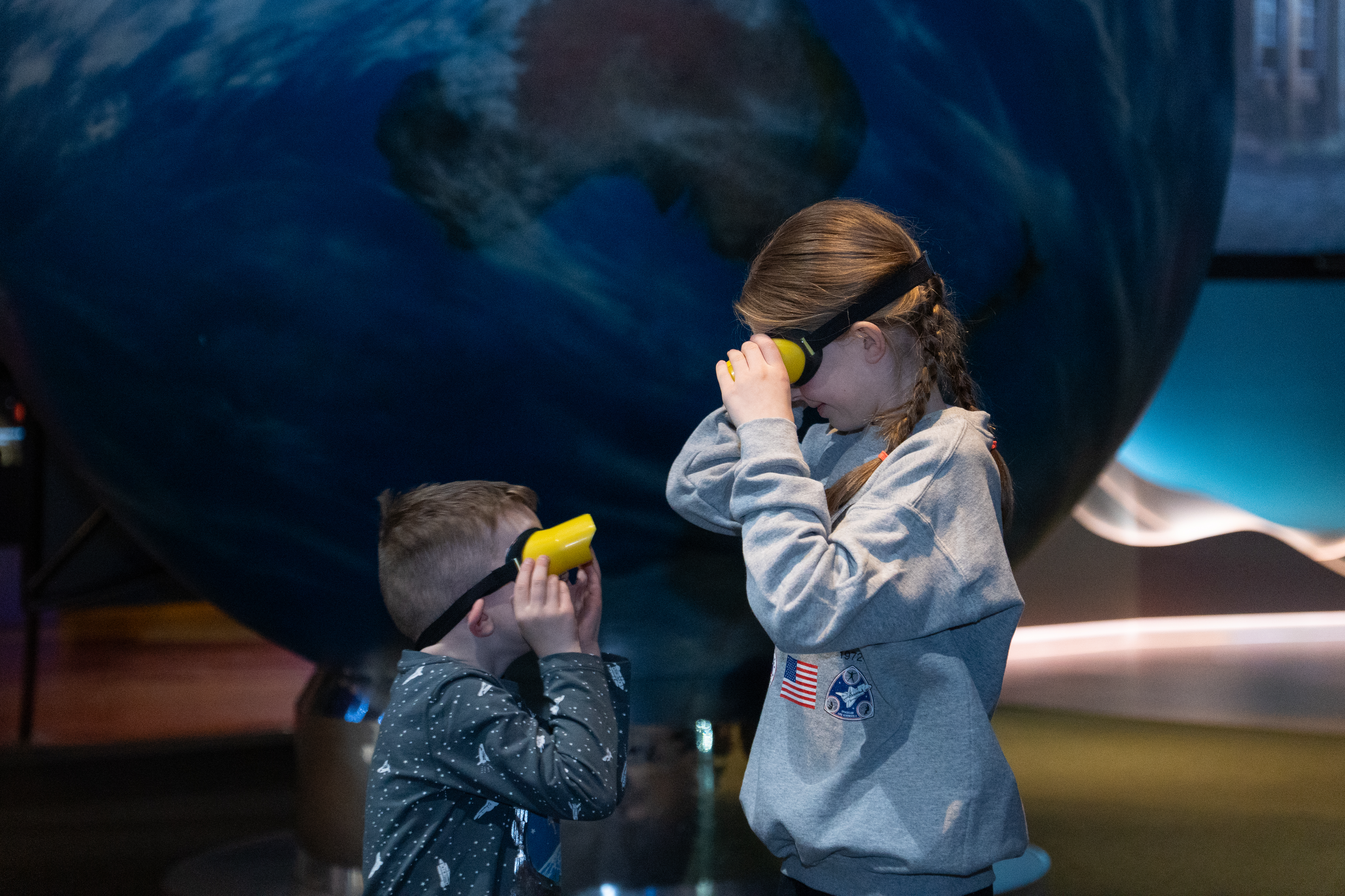 Two children in goggles looking at each other in Home Planet gallery