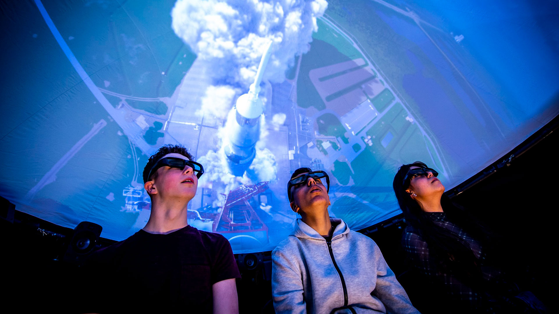 Three young men watch the fulldome show with 3D glasses
