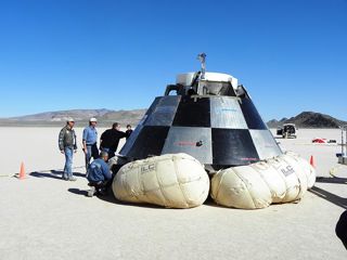 Personnel inspect the CST-100 following the parachute drop test.