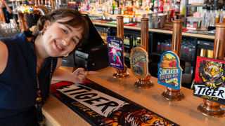 Kat pointing at the Citrus Supernova Beer tap at Everard's