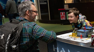 Man in a wheelchair and a happy child playing a game at To Boldly Game