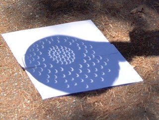 Someone using a colander to view an eclipse as a pinhole projector.