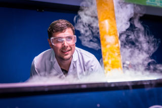 Smiling Science Communicator with PPE hosts a chemistry demonstration 