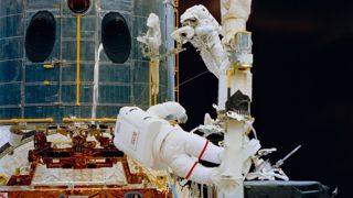 Astronauts Jeffrey A. Hoffman (bottom) and F. Story Musgrave (top) are both working on Hubble Space Telescope during Servicing Mission 1.