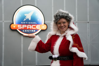 Mrs Santa in front of National Space Centre Logo