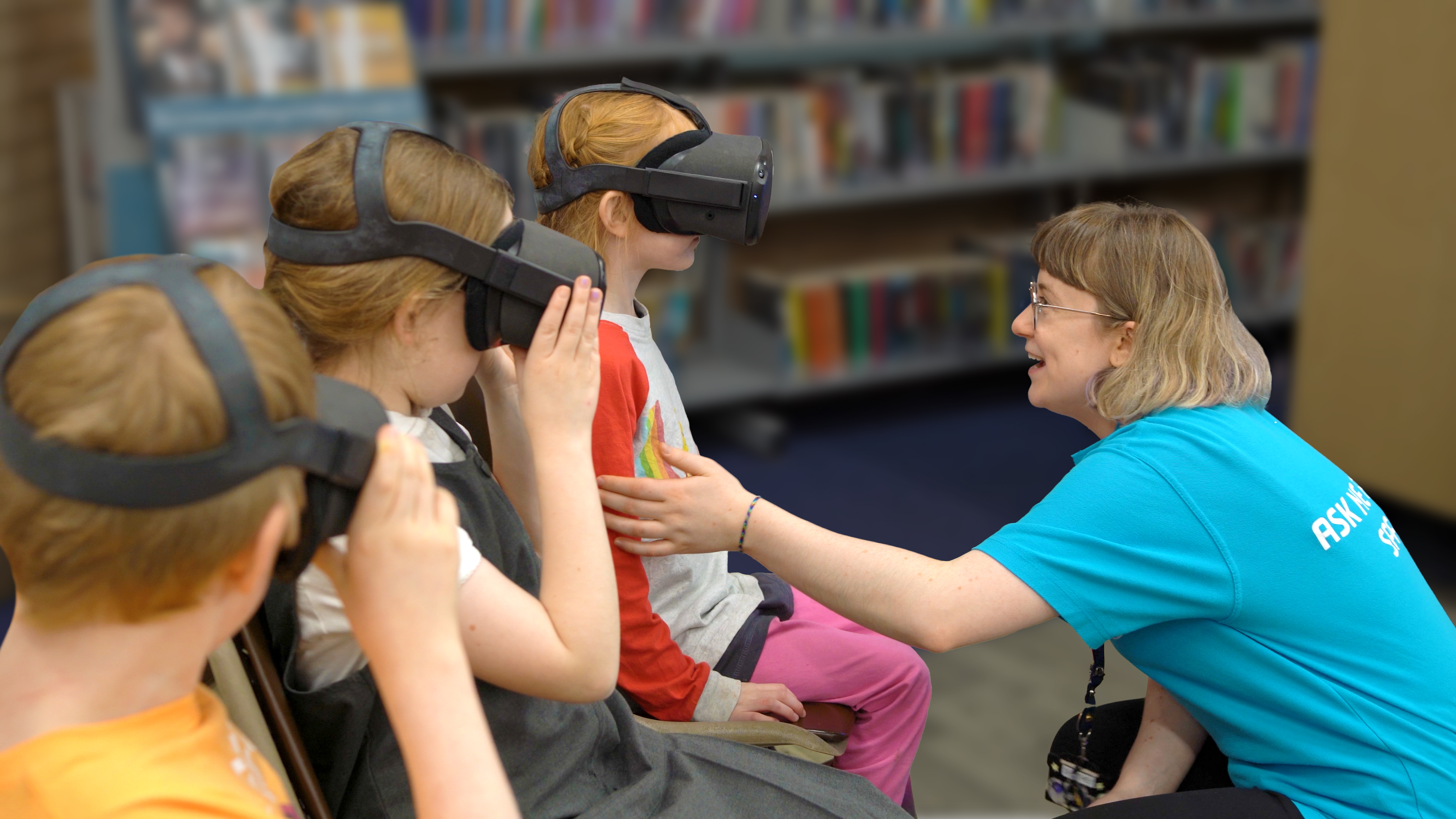 A member of staff is supervising three children wearing VR headsets.