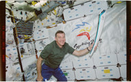Astronaut Jim Voss is holding a replica of the 2000 Olympic Torch onboard the Space Shuttle Atlantis.